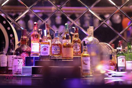 a group of bottles of alcohol sitting on a bar at Goa Country Club Near Park Hospital BY Pearl I Luxury resort in Gurgaon in Gurgaon