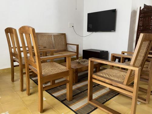 a room with a table and chairs and a tv at Traditional Kerala Home in Kollam