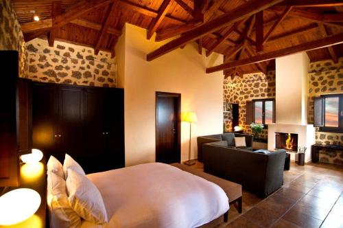 a bedroom with a bed and a living room with a fireplace at Pliadon Gi Mountain Resort & Spa in Kato Trikala Korinthias