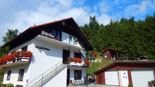 a white building with red flowers on the balconies at Apartments Dar in Lokve