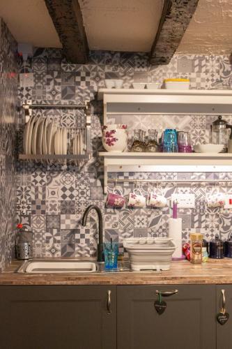 a kitchen with a sink and a tile wall at Longbridge Cottage in Shepton Mallet