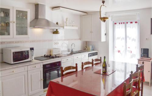 a kitchen with white cabinets and a table and a microwave at 2 Bedroom Nice Home In Plonevez Porzay in Plonévez-Porzay