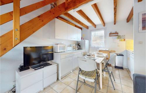 une cuisine avec une table, une télévision et des placards blancs dans l'établissement Beautiful Home In Ronce-Les-Bains, à Ronce-les-Bains