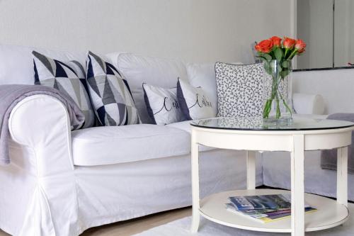 a white couch with pillows and a vase of flowers on a table at Nostalgie-Loft in Mayen
