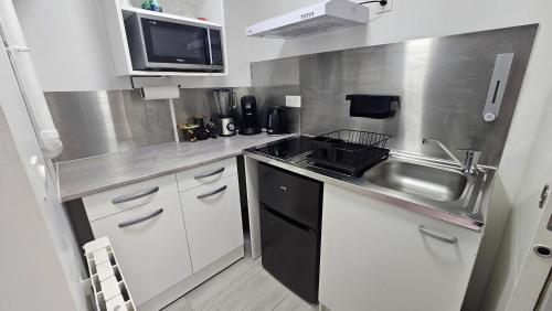 a small kitchen with a sink and a microwave at Maisonnette grande hauteur in Drancy
