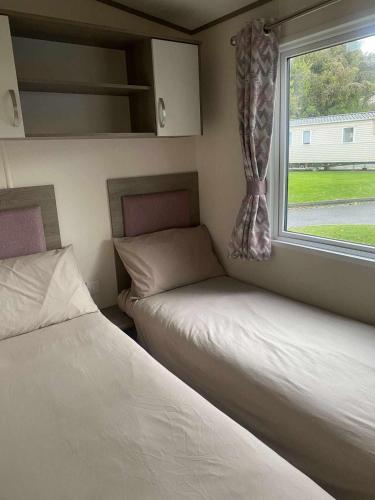 two beds in a small room with a window at Kiln Park in Tenby