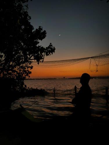 a person sitting on the beach watching the sunset at Traditional Kerala Home in Kollam