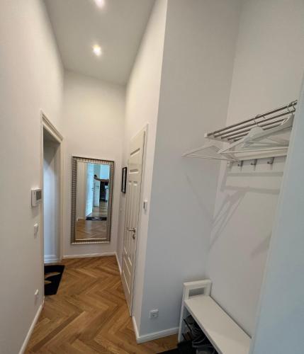 a hallway with white walls and a staircase with a mirror at Deluxe Apartments mit Arbeitsplatz im Denkmalhaus, beste und ruhige zentrale Lage von Halle Saale WE1 in Halle an der Saale
