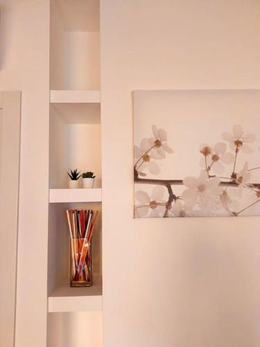 a shelf with a vase with flowers in it at A casa di Gio e Fede in Rimini