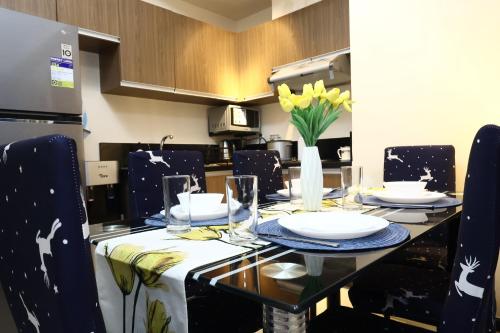 a dining table with plates and glasses and a vase of flowers at Bayfront Suite in Pasay, Manila Near NAIA Terminal, PICC, Star City, MOA and US Embassy - Pet-Friendly, Free Pool, Wi-Fi & Netflix in Manila