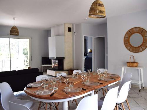 une salle à manger avec une table en bois et des chaises blanches dans l'établissement Spacieuse villa familiale avec terrasses à 500m du Bassin - FR-1-736-21, à Lège-Cap-Ferret