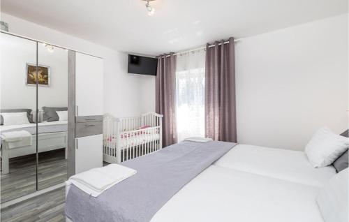 a white bedroom with a bed and a crib at 2 Bedroom Awesome Apartment In Fuzine in Fužine