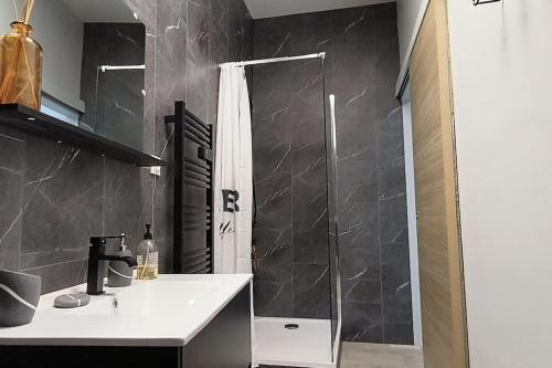 La salle de bains est pourvue d'une douche et d'un lavabo blanc. dans l'établissement Suite Beaulieu 5 - Charmant Appartement Moderne 2 ch- vue Cathédrale, à Angoulême