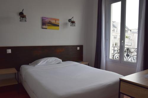 a bedroom with a white bed and a window at Hôtel Résidence Champerret in Levallois-Perret