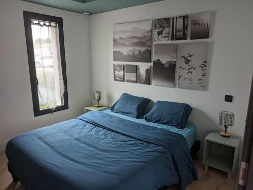 a bedroom with a bed with blue sheets and pictures on the wall at Rez de jardin proche mer in Arradon