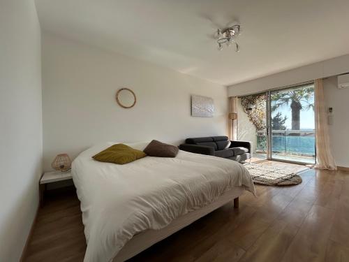 a white bedroom with a bed and a living room at Sea view flat with car park boarder Cannes in Le Cannet