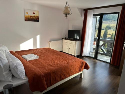 a bedroom with a bed and a television and a window at Conacul Munții Bucovinei in Câmpulung Moldovenesc