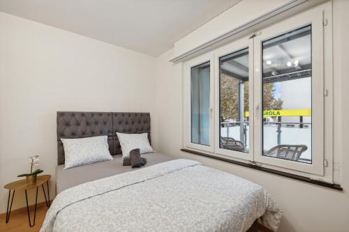 a bedroom with a bed and a large window at Pearlstay - City Center Workplace Balcony Washer in Winterthur