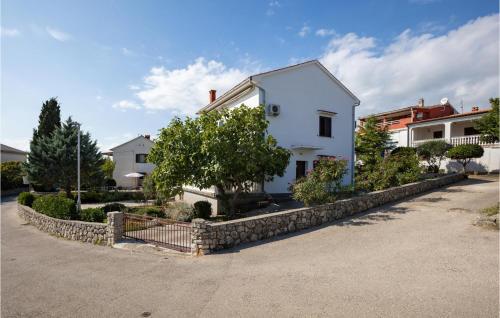 a white house with a stone retaining wall at Cozy Apartment In Krk With Wifi in Krk
