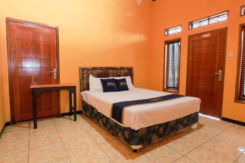 a bedroom with a bed and a table in it at Artana Guest House By ARBA in Palayangan