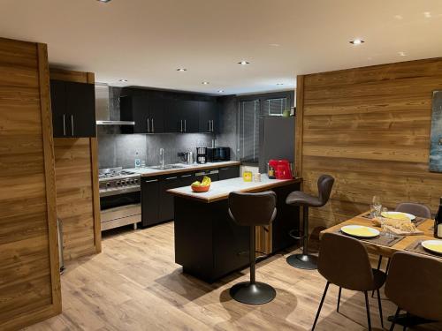 a kitchen with black cabinets and a table with chairs at Appartement Tetra in Bourg-Saint-Maurice