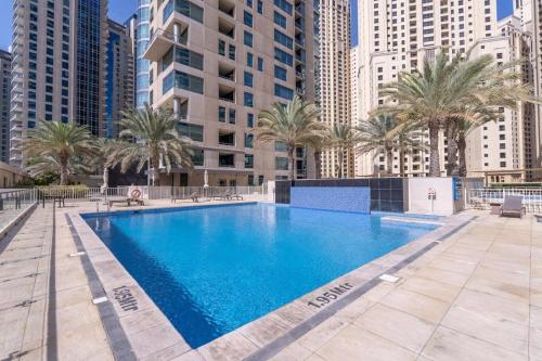 a large swimming pool with palm trees and buildings at 2 Bedroom Apartment full Marina View in Dubai