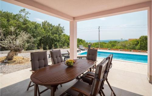 a wooden table and chairs on a patio with a pool at Beautiful Home In Koromacno With Wifi in Koromačno