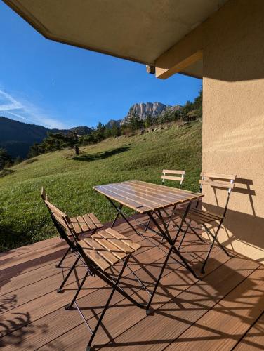 une table de pique-nique et deux chaises sur une terrasse dans l'établissement Appartement La Canopée, à Gresse-en-Vercors
