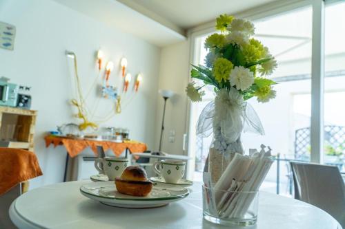 a table with a vase of flowers and plates on it at Percebes Exclusive B&B in Cutrofiano