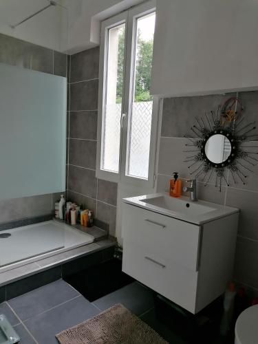 une salle de bain avec un lavabo, une baignoire et un miroir dans l'établissement Maison sansonnette, à Guérigny