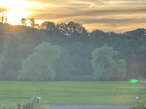 a sunset over a field with a fence and trees at Chalet 9 La Boverie in Rendeux