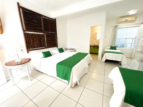 a hotel room with two beds and a table at Pousada Bucaneiro in Búzios