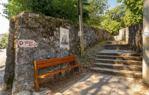 a wooden bench sitting next to a stone wall with stairs at 1 Bedroom Stunning Apartment In Lovran in Lovran