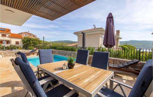 a patio with a wooden table and chairs and an umbrella at 3 Bedroom Nice Home In Kornic in Kornić