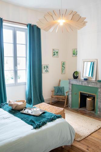 - une chambre avec un lit doté de rideaux bleus et d'une cheminée dans l'établissement Le jardin de Gassiot offre étape pro, à Saint-Quentin-de-Baron