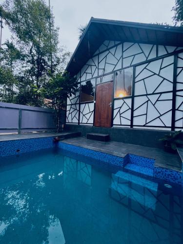 a house with a swimming pool in front of a building at Josh Holidays Wayanad Resort - Every Room with Attached Private Pools in Vaduvanchal