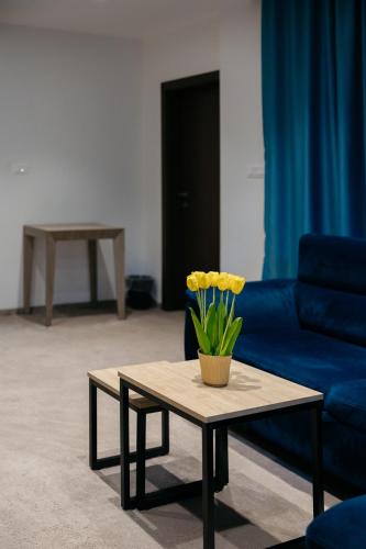a coffee table with a vase of yellow flowers on it at Hotel Gradche in Kochani