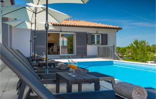 una piscina con sedie e ombrelloni accanto a una casa di Villa Aurora Labin a VeliGolji
