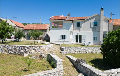a large white house with a stone wall at 1 Bedroom Amazing Apartment In Podgrade in Slime