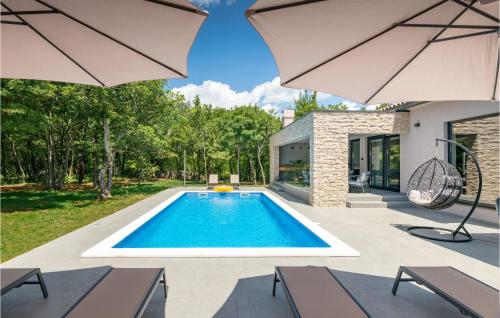 una piscina nel cortile di una casa con ombrelloni di Amazing Home In Labin With Sauna a Labin