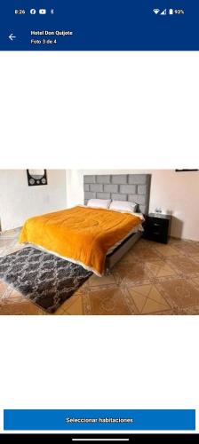 a bed with a orange blanket on top of it at Hotel Don Quijote in Mineral de Pozos