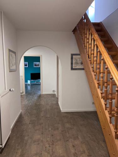 a hallway with a wooden staircase in a house at Ferienhaus Sonnendeich in Emmelsbüll-Horsbüll