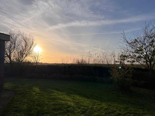 a sunset over a field with the sun in the sky at Ferienhaus Sonnendeich in Emmelsbüll-Horsbüll