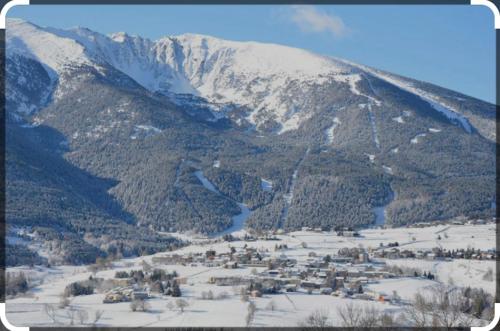 a snow covered mountain with a town in the foreground at Chalet des loulous , 3 chambres, 8 couchages in Font Romeu Odeillo Via