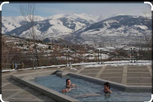 two people in a swimming pool with mountains in the background at Chalet des loulous , 3 chambres, 8 couchages in Font Romeu Odeillo Via