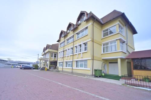 a yellow building with a car parked in a parking lot at Romblast Srl in Găgeni