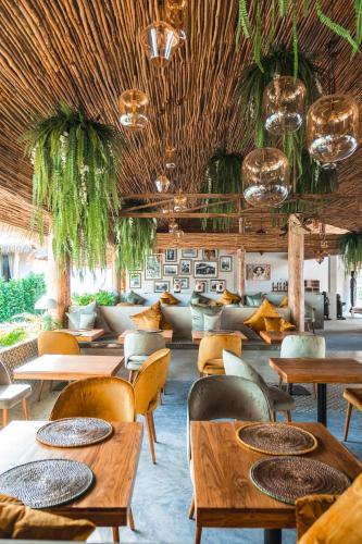 a restaurant with tables and chairs and plants on the ceiling at The Deck Cottages Samui in Bophut
