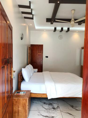 a bedroom with a large bed with white sheets at Wavealokam Beach Retreat in Varkala