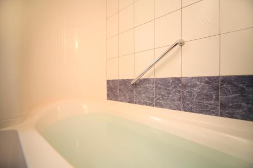 a white bath tub in a bathroom with tiles at Vessel Hotel Kumamoto Airport in Ozu