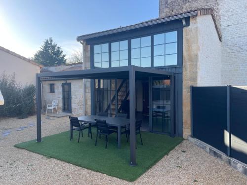 a glass pavilion with a table and chairs on grass at Maison chaleureuse avec parking sur place in Saint-Gelais